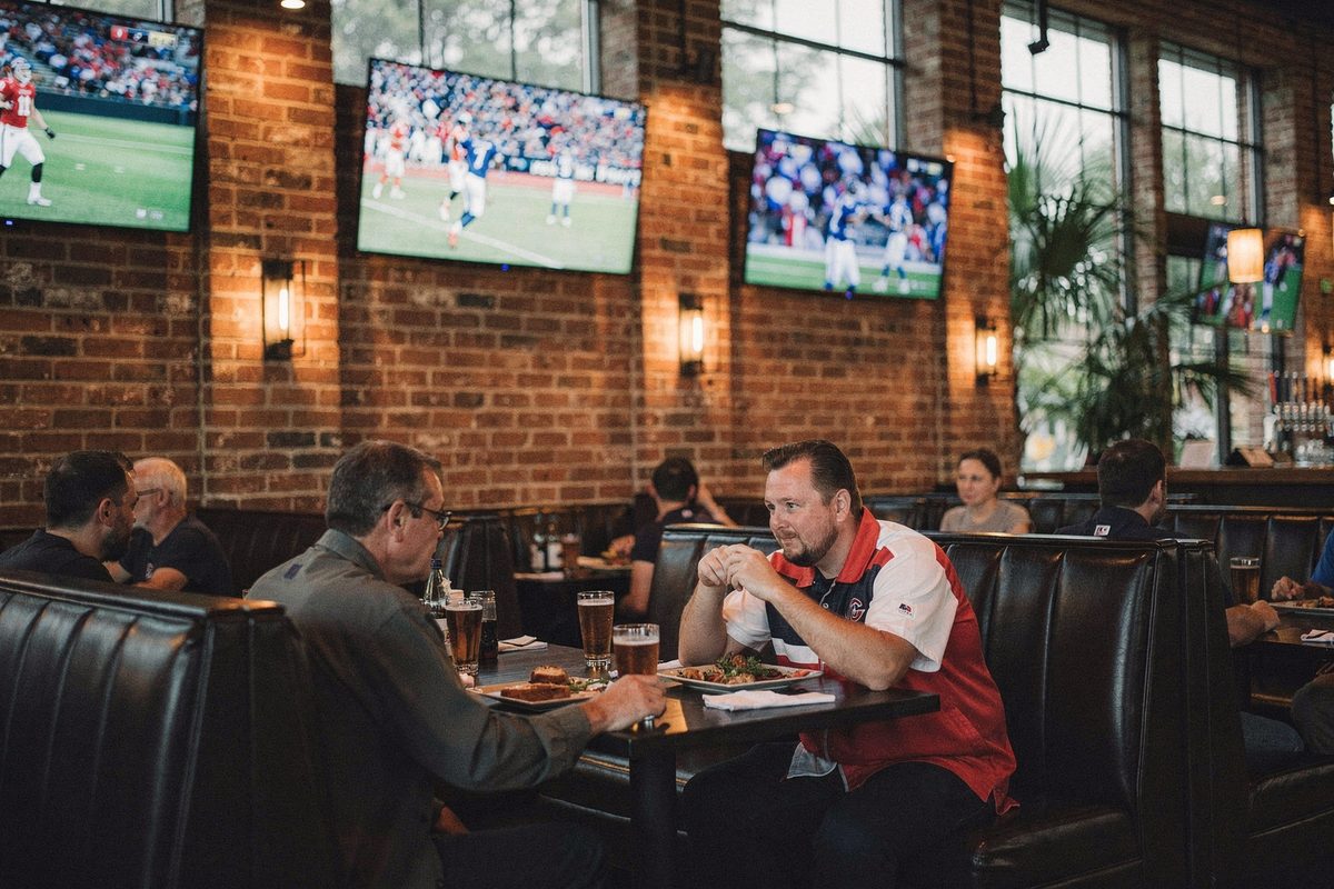 Sports lounge booths with overhead screens showing live game broadcasts